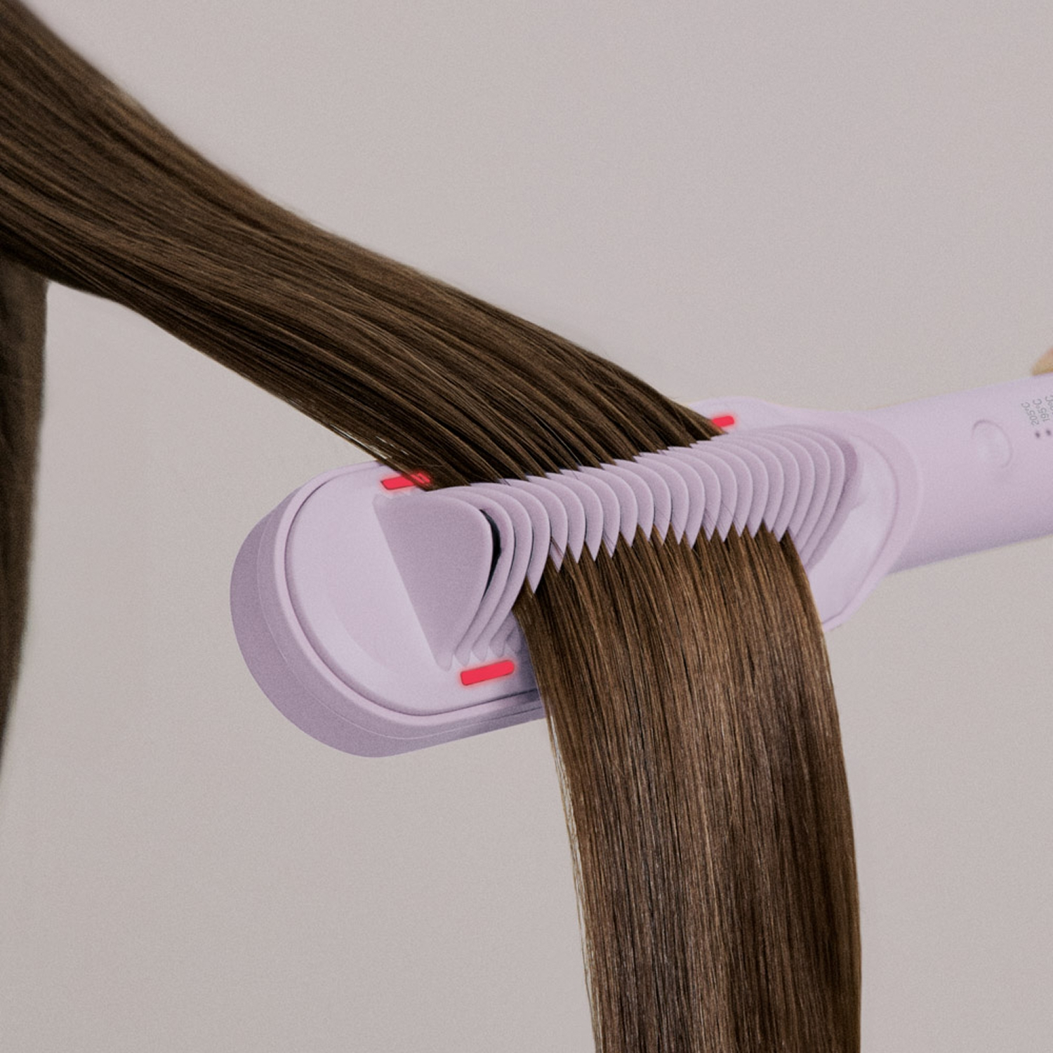 Una plancha de pelo de color morado claro deslizándose por cabello castaño largo y liso sobre fondo neutro.