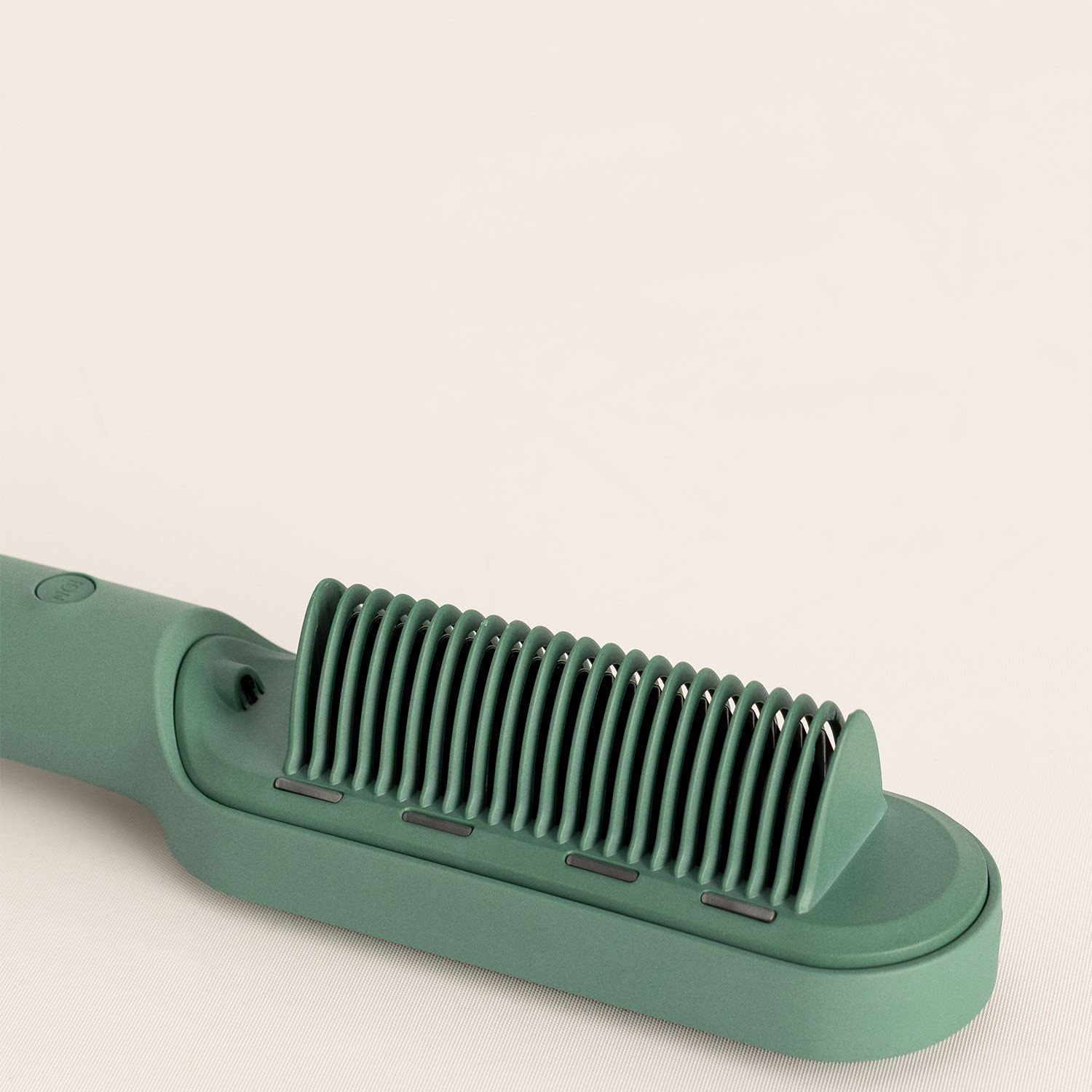 Cepillo alisador de pelo verde con dientes integrados sobre una superficie clara.