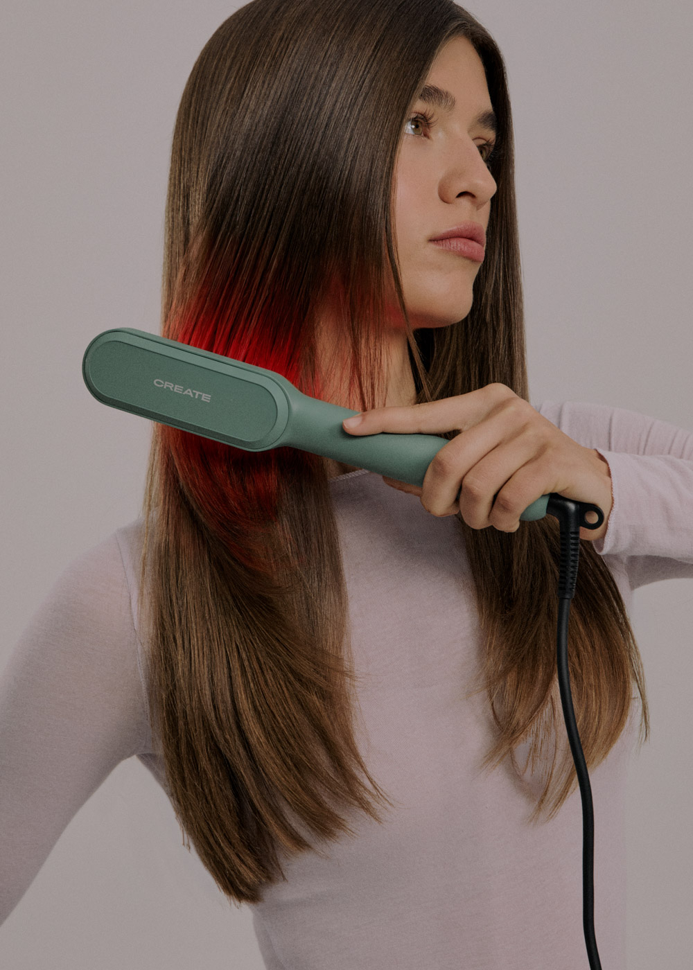 Mujer alisa cabello castaño con degradado rojo usando una plancha verde Create.