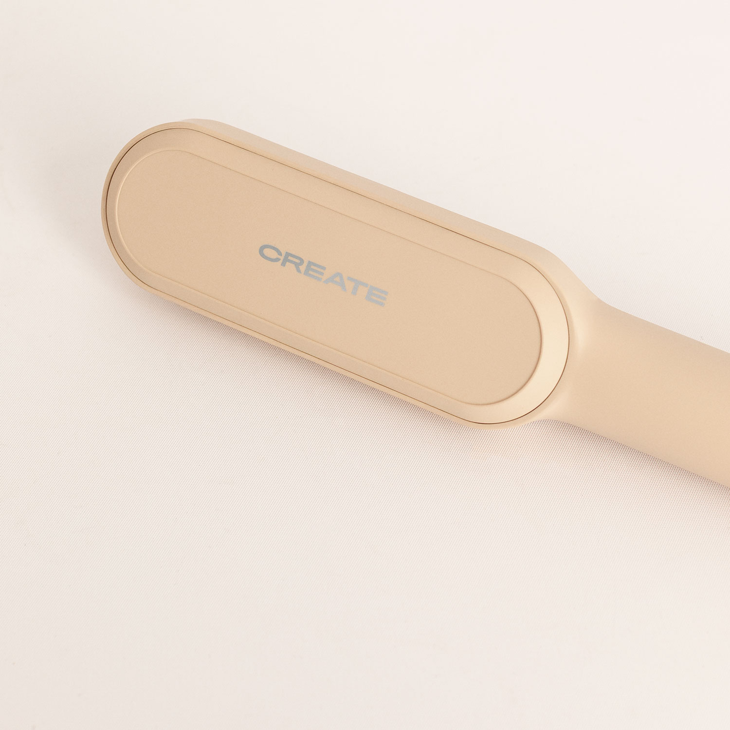 Una plancha de pelo de color beige con la inscripción CREATE sobre fondo claro.