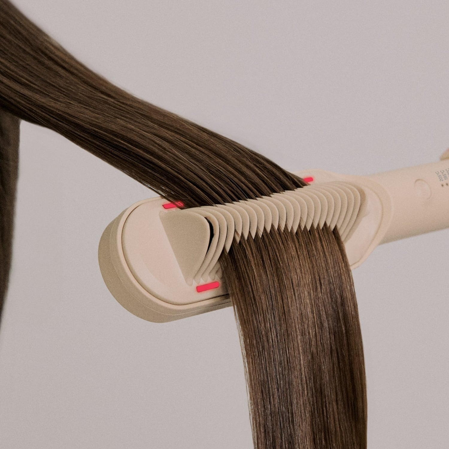 Cabello castaño largo alisado con una plancha beige con dientes integrados.