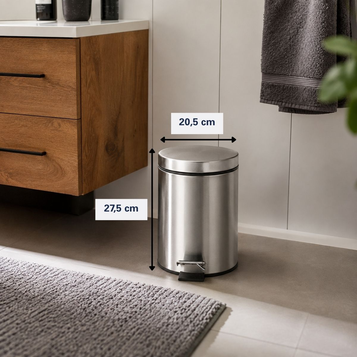 Poubelle à pédale en acier inoxydable dans une salle de bains, avec des dimensions de 20,5 cm de largeur et 27,5 cm de hauteur.