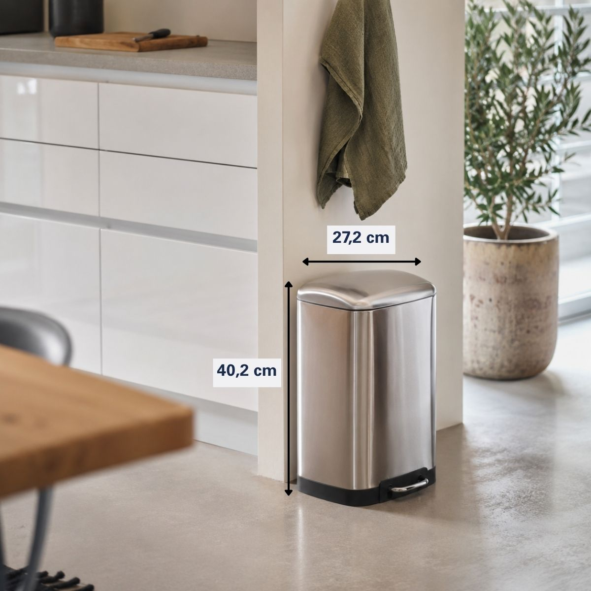 Une poubelle à pédale argentée dans une cuisine moderne avec des dimensions de 27,2 cm de large et 40,2 cm de haut.