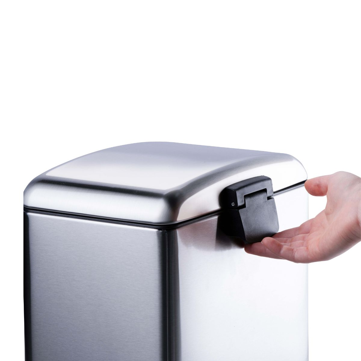 Une main ouvre le loquet noir d'une poubelle en acier inoxydable.