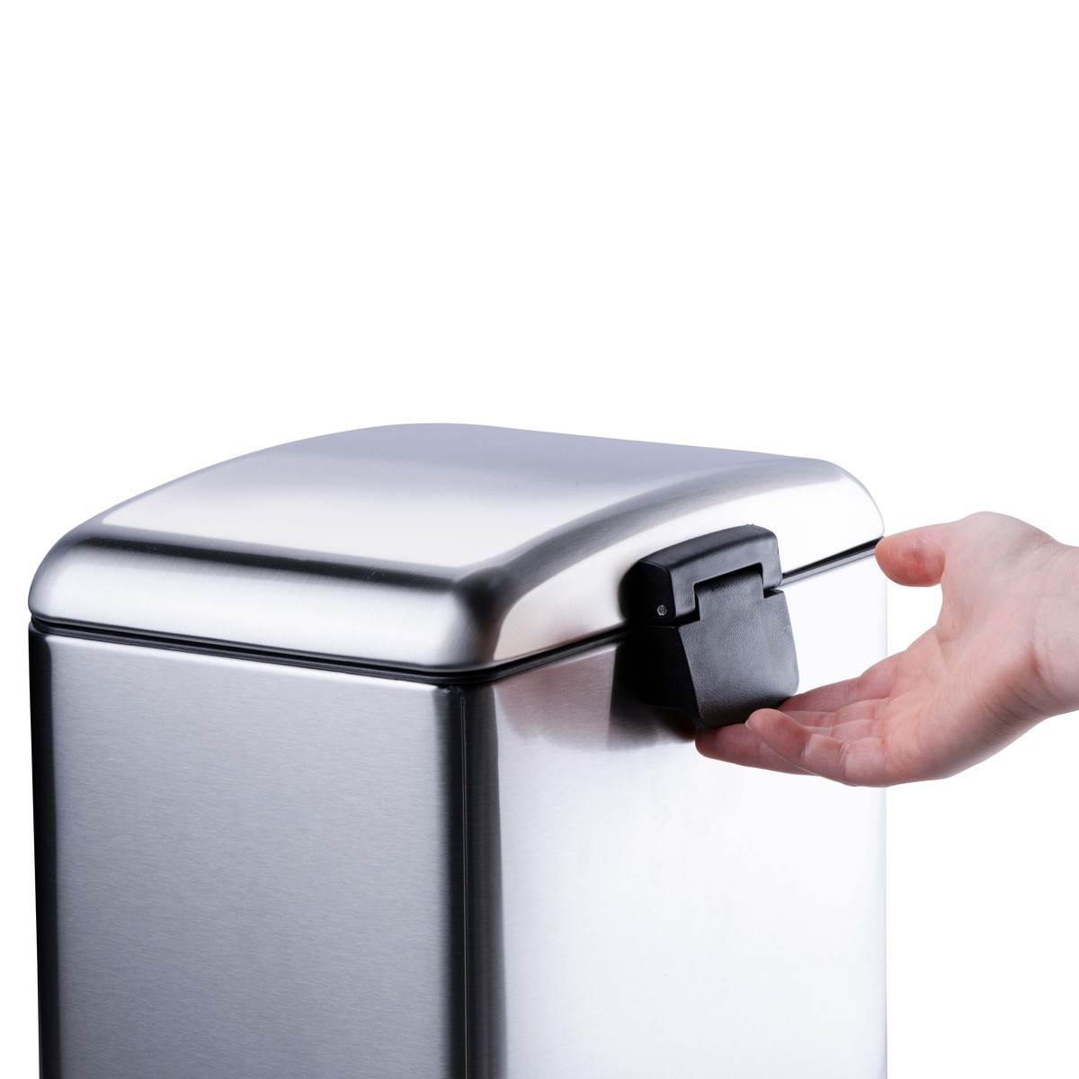 Une main ouvre le couvercle d'une poubelle carrée en acier inoxydable sur fond blanc.