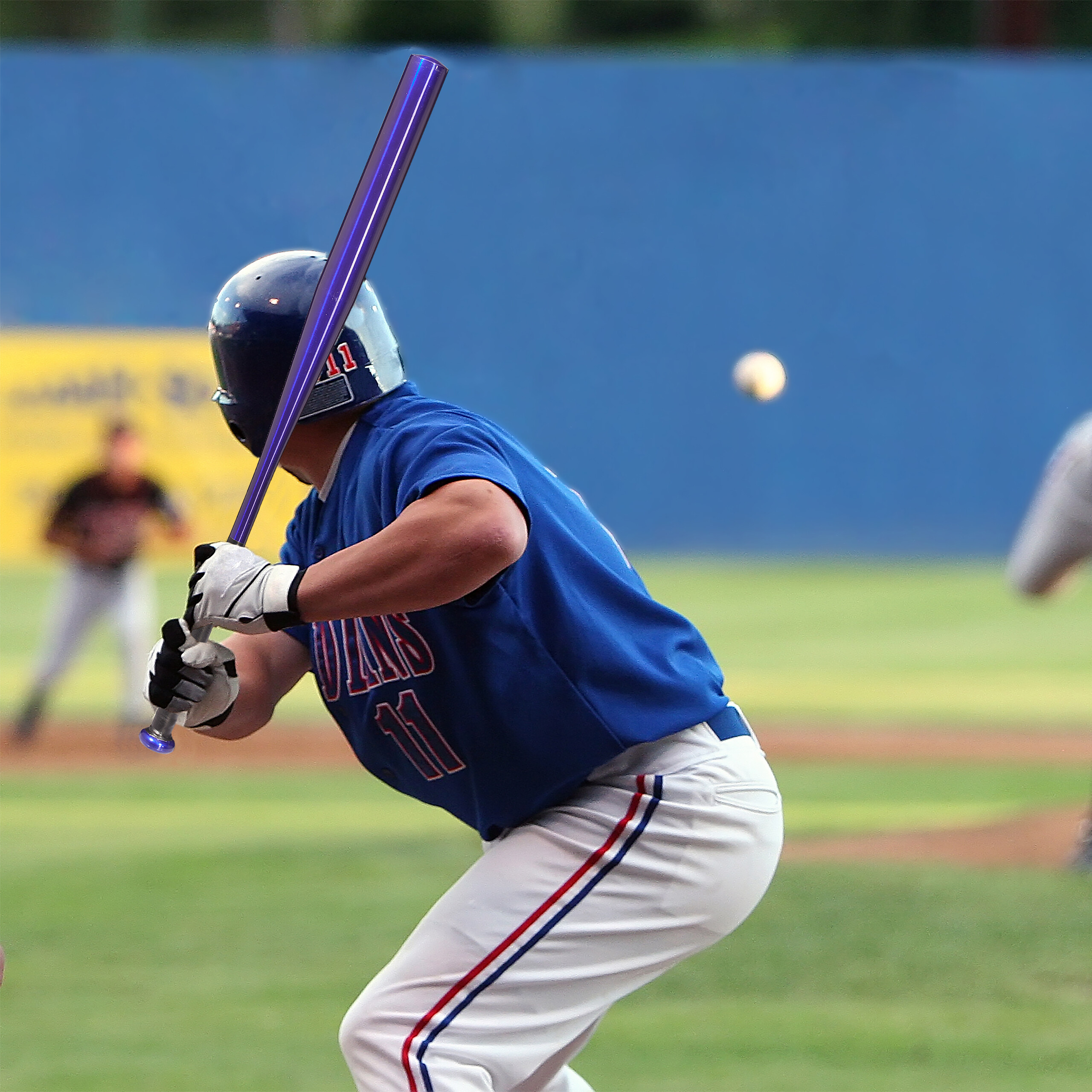 Ein Baseballspieler in blauer Uniform schwingt einen lila Schläger auf dem Feld.