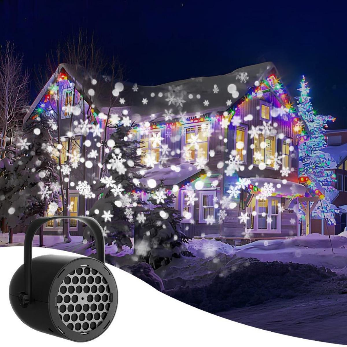Ein Projektor im Vordergrund wirft tanzende Schneeflocken auf ein beleuchtetes Haus in einer Winternacht.