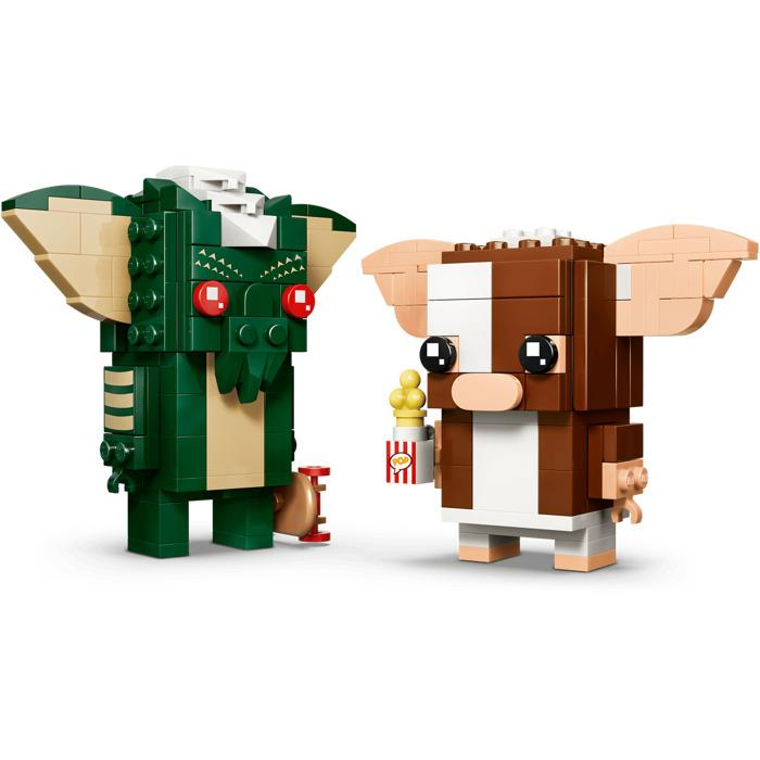 Beyaz arka planda kaykay tutan yeşil bir Gremlin ve patlamış mısır tutan kahverengi bir Gizmo olmak üzere iki Lego figürü.