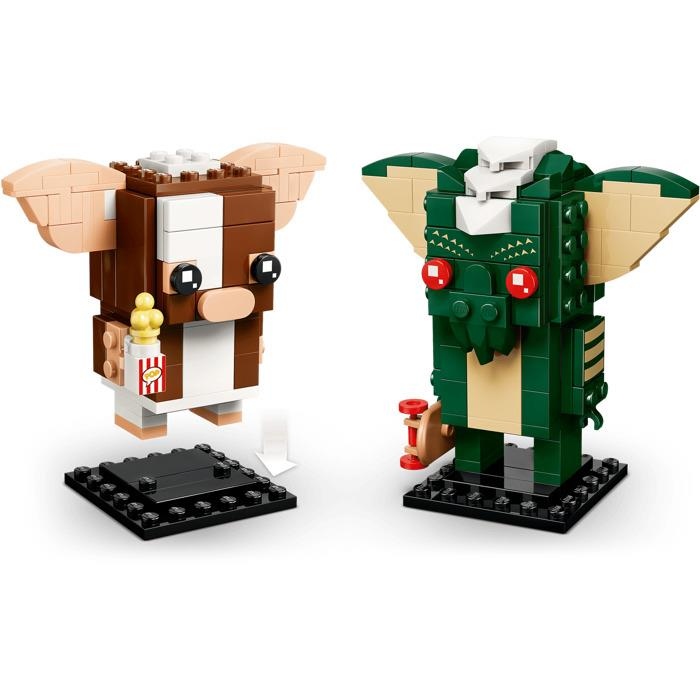 Siyah stantlar üzerinde iki Lego Gremlins figürü, solda patlamış mısır tutan Gizmo ve sağda kaykaylı Stripe.