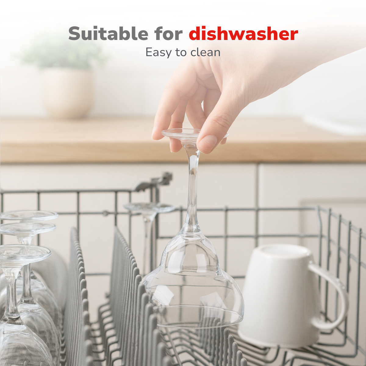 A hand places a wine glass into a dishwasher rack, with other glasses and a white mug nearby.