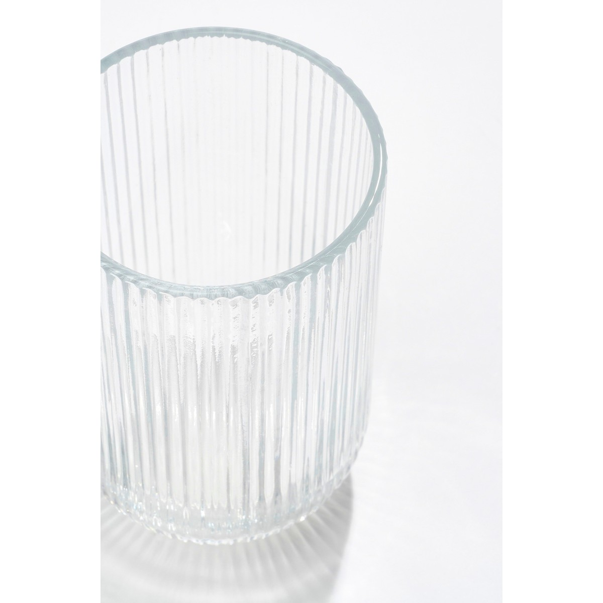 A clear, vertically ribbed glass tumbler on a white background with soft shadows.
