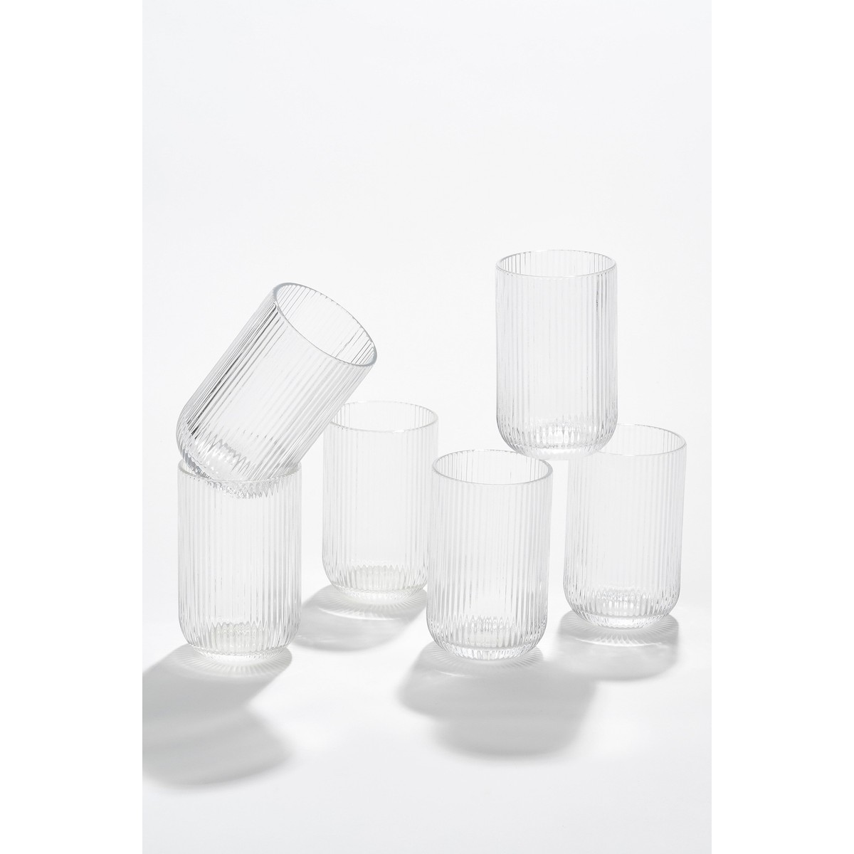 Six ribbed clear glasses are arranged in an appealing composition on a white background.