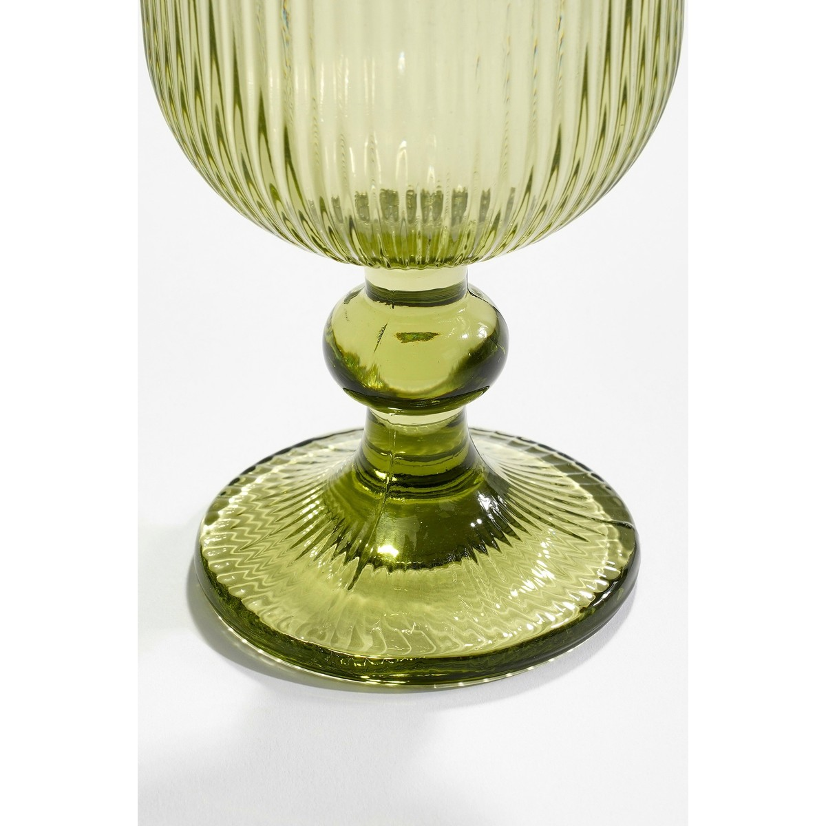 A close-up of a green ribbed glass goblet against a plain white background.