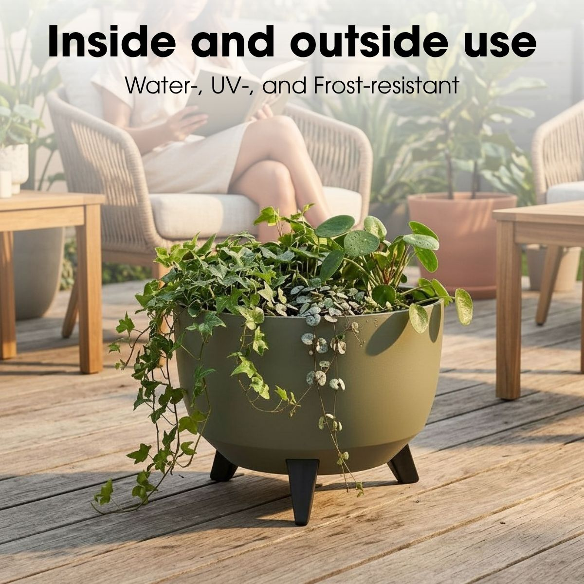 Jardinière ronde verte sur pieds noirs remplie de diverses plantes vertes sur une terrasse en bois.