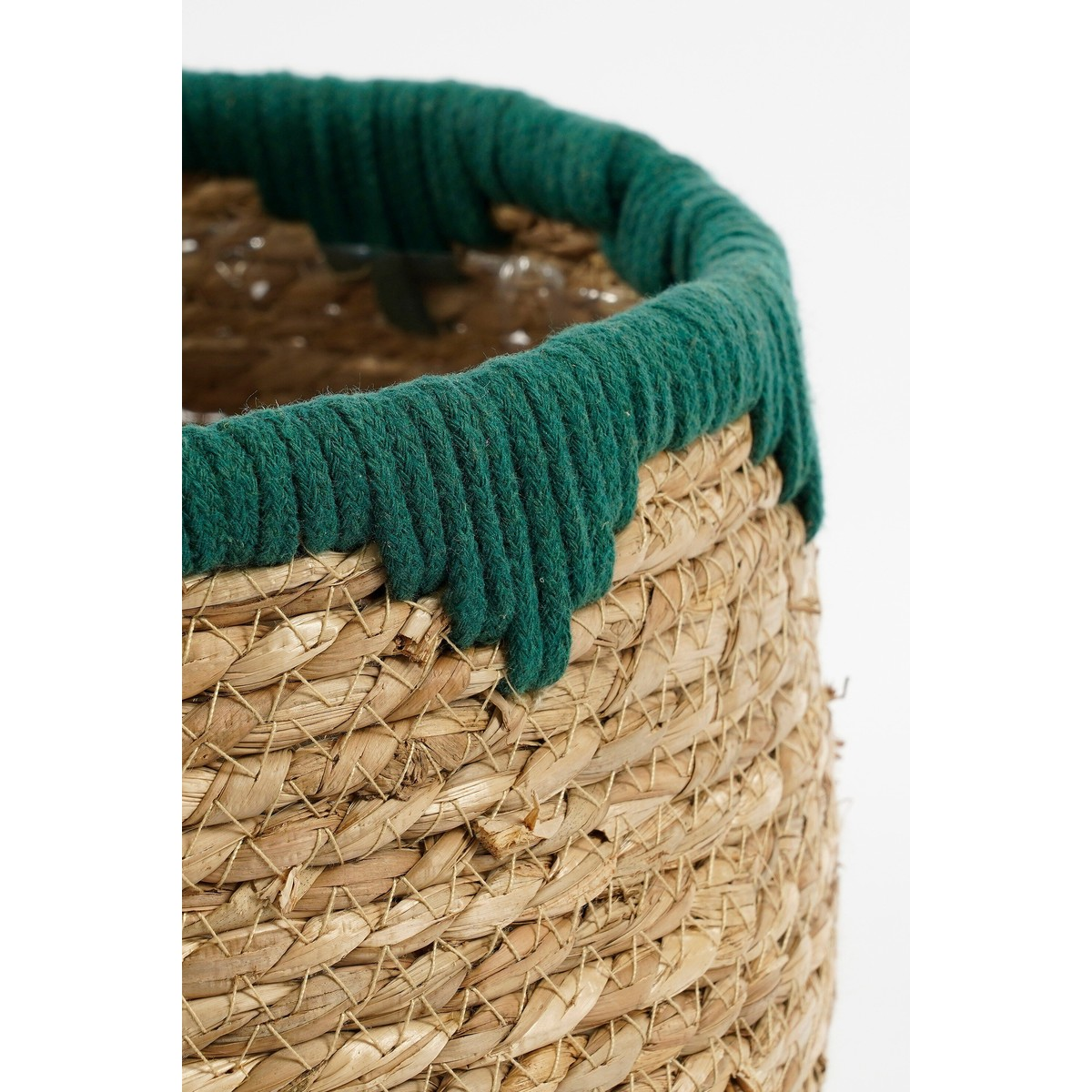Gros plan d'un panier tressé avec une épaisse corde verte autour du bord sur fond blanc.