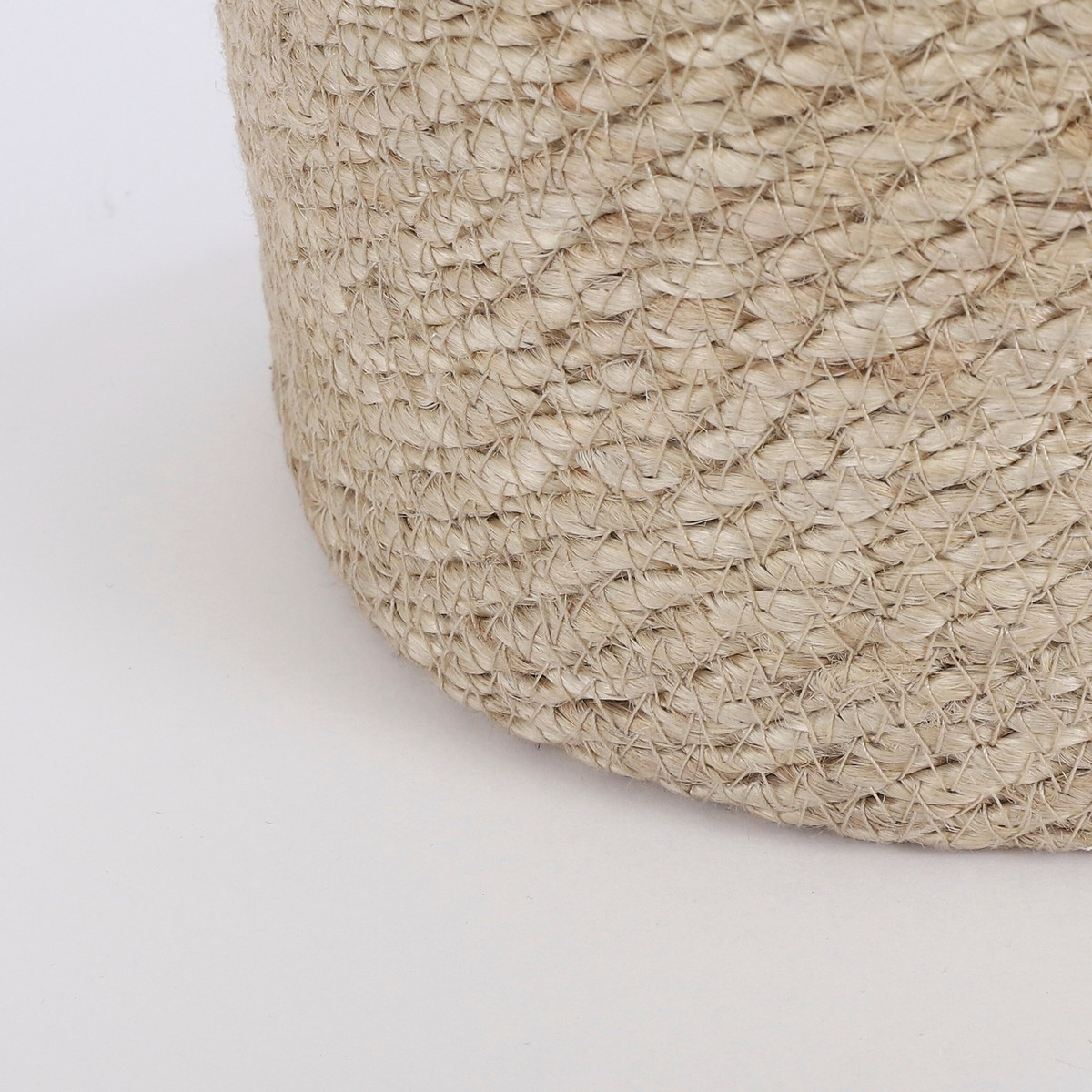 Gros plan sur un panier de rangement en jute beige tissé sur fond blanc.