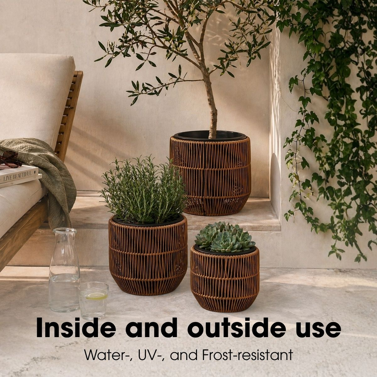 Trois pots en rotin marron avec des plantes, une bouteille en verre et un verre sur un sol en pierre.