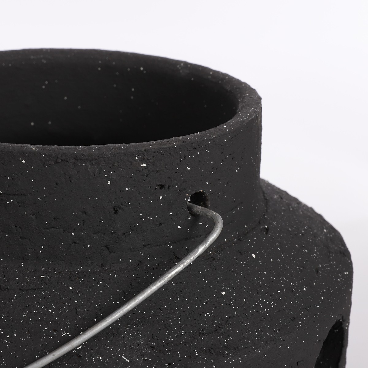 Zwarte getextureerde pot met witte spikkels en metalen handvat tegen witte achtergrond.