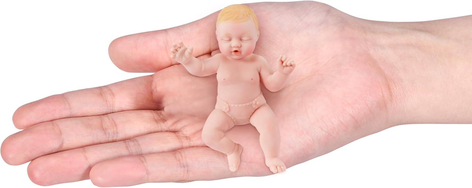 Eine kleine, lebensechte Puppe in Form eines Babys liegt flach auf einer offenen menschlichen Hand.