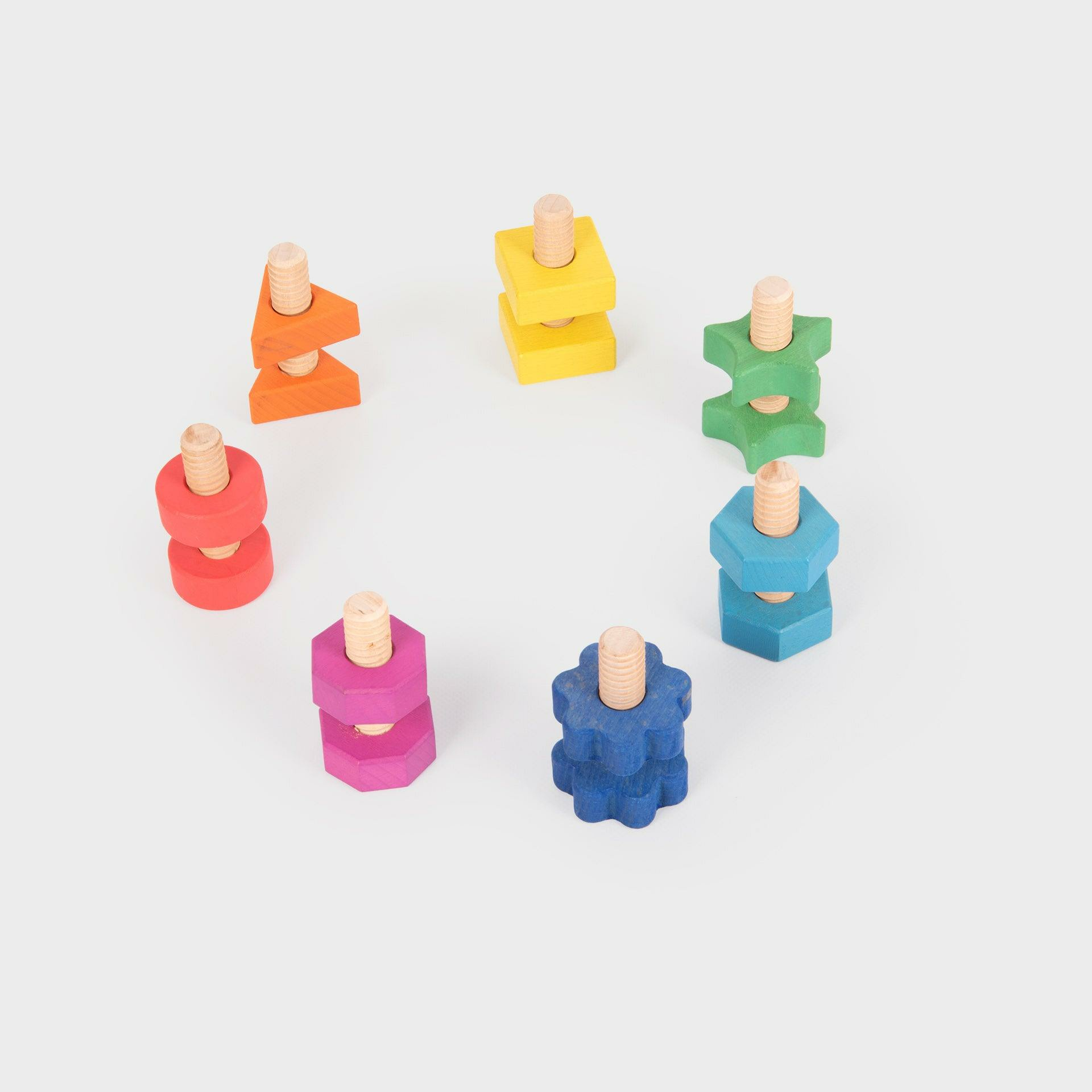Sechs bunte Holzspielzeuge mit Schrauben und Muttern im Kreis auf weißem Hintergrund.