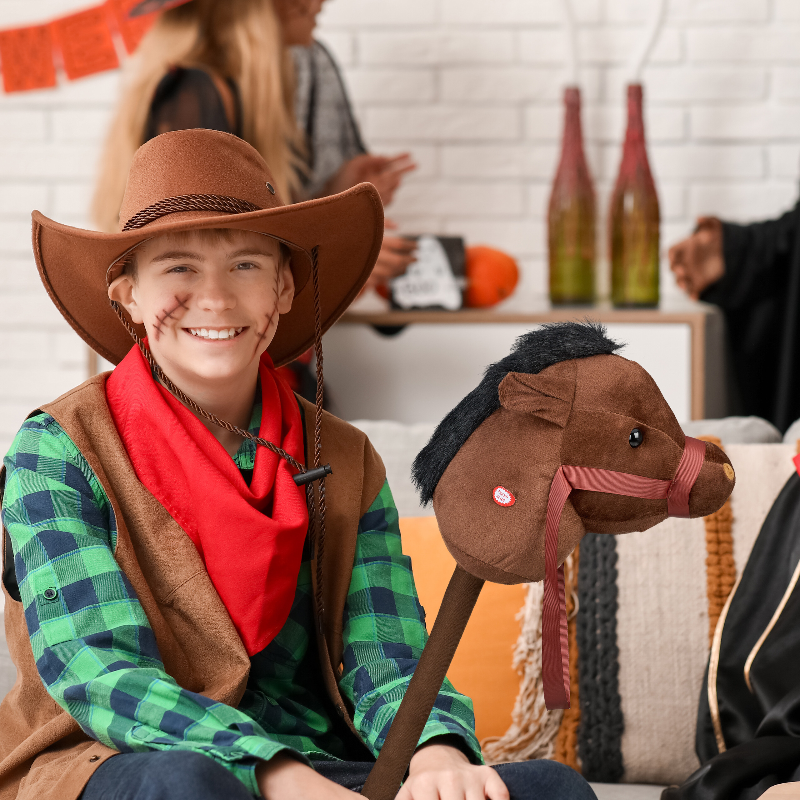 Ein Junge im Cowboy-Kostüm mit einem Steckenpferd, im Hintergrund Personen und Flaschen.