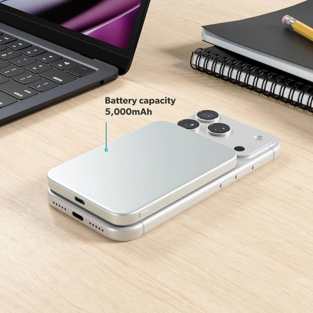 Eine Powerbank mit 5.000 mAh Akku liegt auf einem Smartphone, neben einem Laptop und Notizbuch.