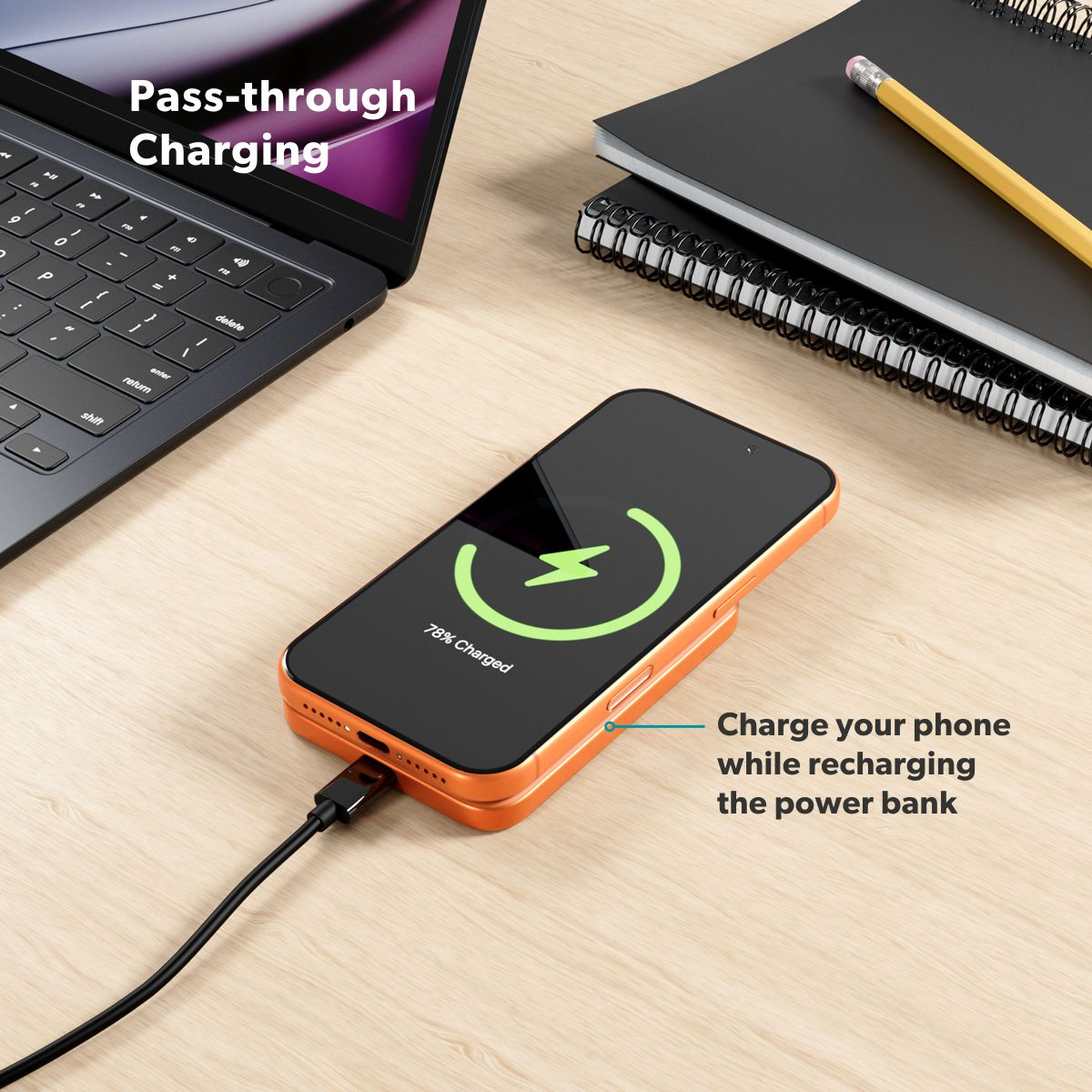 Ein orangefarbenes Smartphone wird auf einem Holztisch mit Laptop und Notizbuch aufgeladen.