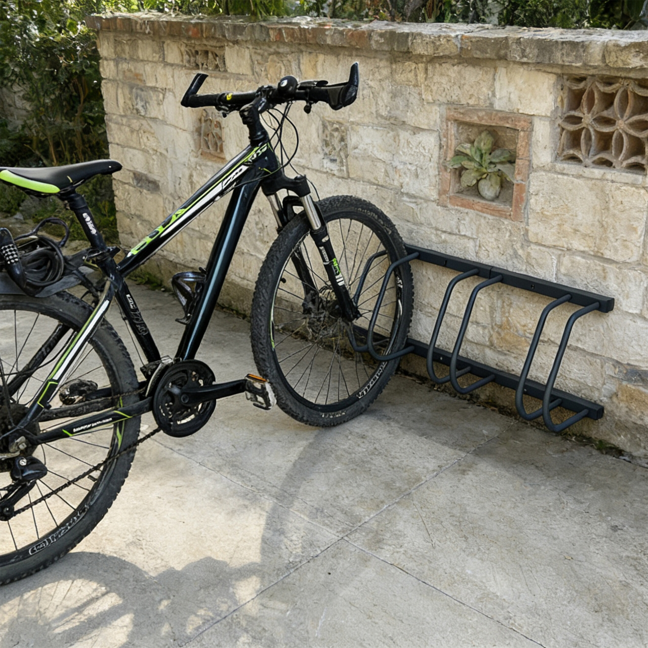 Ein schwarzes Mountainbike parkt in einem Metallständer an einer rustikalen Steinmauer.