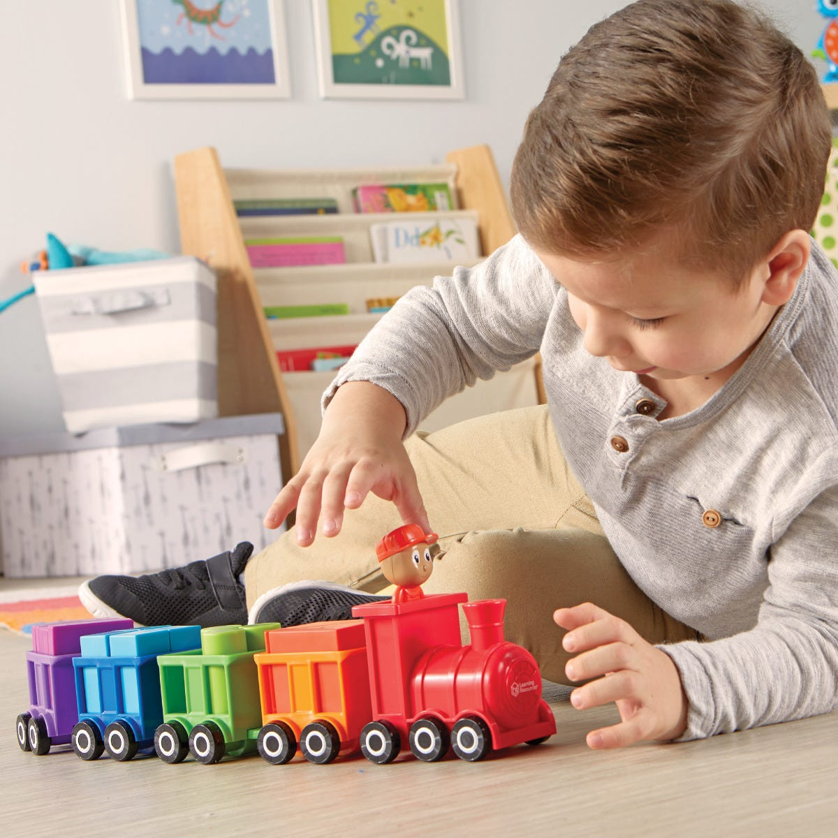 Kleiner Junge spielt im Kinderzimmer mit einem bunten Spielzeugzug.