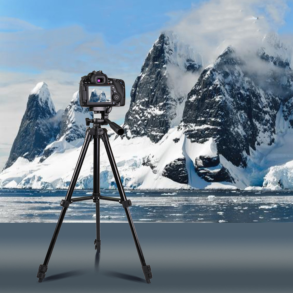 Eine DSLR-Kamera auf einem Stativ steht vor einer verschneiten Berglandschaft und einem eisigen Meer.