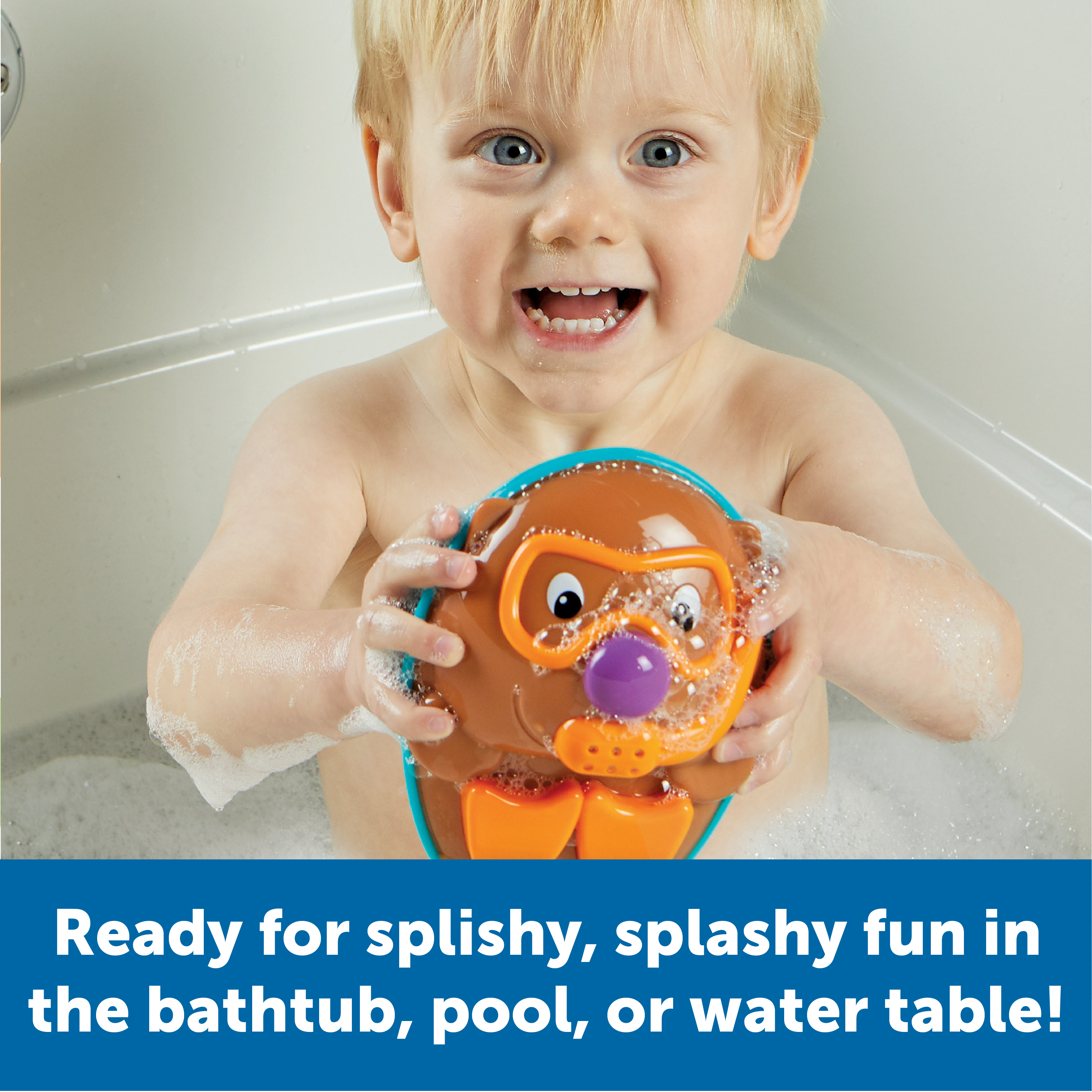Kleinkind lächelt in der Badewanne und hält ein Biber-Wasserspielzeug.