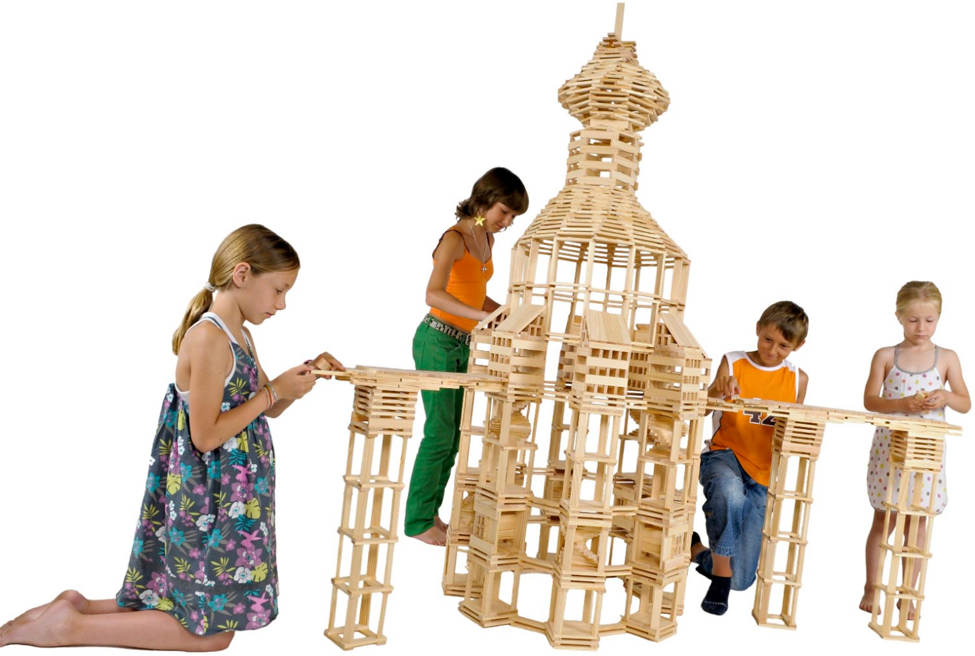 Vier Kinder bauen vor einem schlichten weißen Hintergrund einen hohen, filigranen Turm aus Holzklötzen.