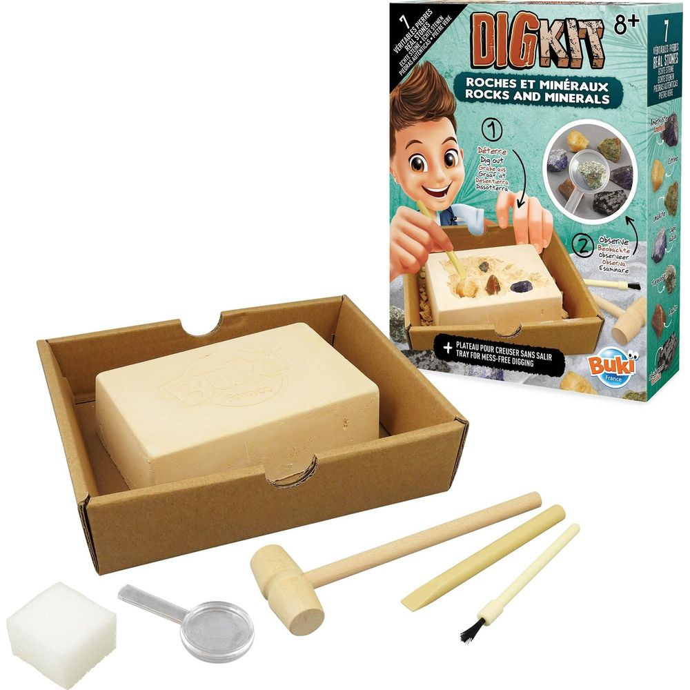 Ein Ausgrabungsset mit Block, Holzhammer, Meißel, Pinsel, Lupe und Schwamm vor einer bunten Produktverpackung.