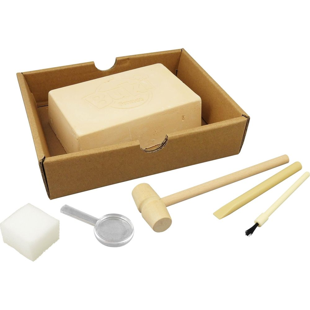 Ein Steinblock in einem Karton mit Holzhammer, Meißel, Pinsel, Lupe und einem Schwamm auf weißem Hintergrund.
