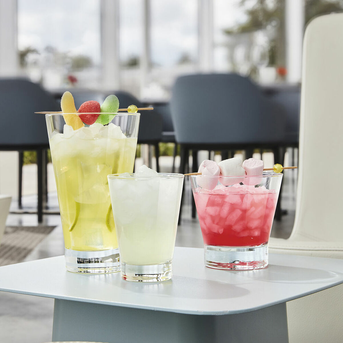 Drei bunte Cocktails mit Eis auf einem Tisch in einem Restaurant.