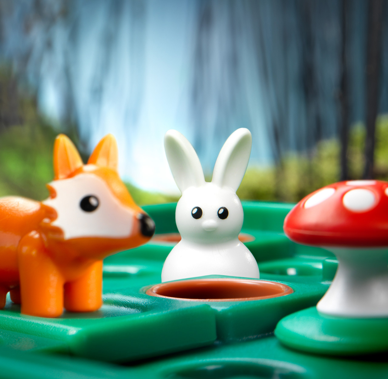 Spielzeugfuchs, weißes Kaninchen und roter Pilz auf einem grünen Brett.