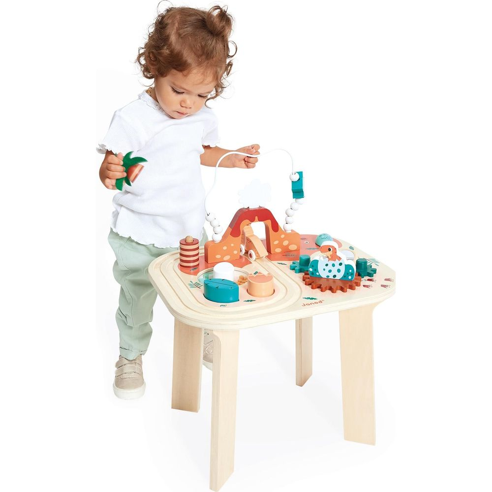 Kleinkind spielt an einem bunten Holztisch mit Dinosaurier-Motiven und Steckspielen.