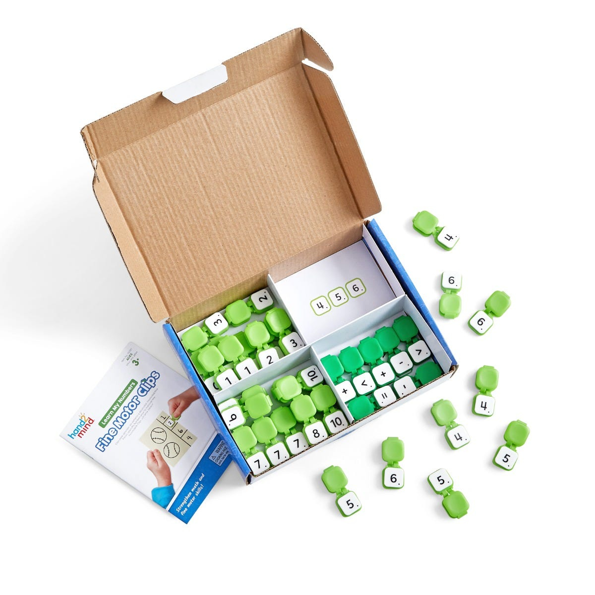 Open cardboard box with green numbered clips, math cards, and instruction booklet on a white surface.