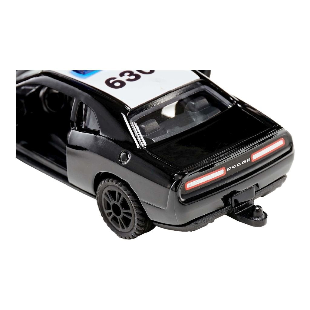 Ein schwarzes Spielzeug-Polizeiauto von Dodge mit weißem Dach, Nummer 630, offener Tür und Anhängerkupplung.