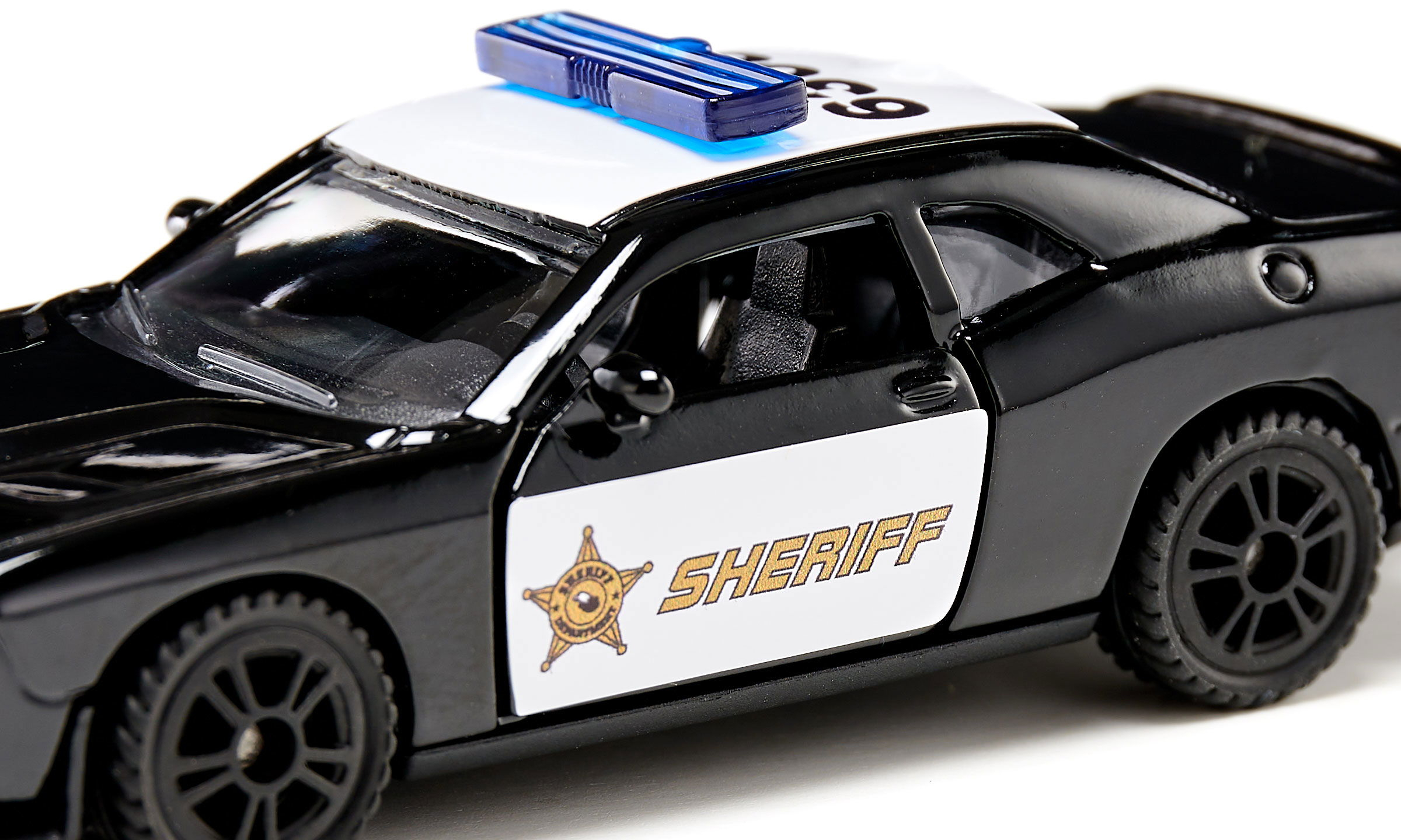 Ein schwarz-weißes Polizei-Spielzeugauto mit blauem Blaulicht und der Aufschrift SHERIFF auf der Tür.