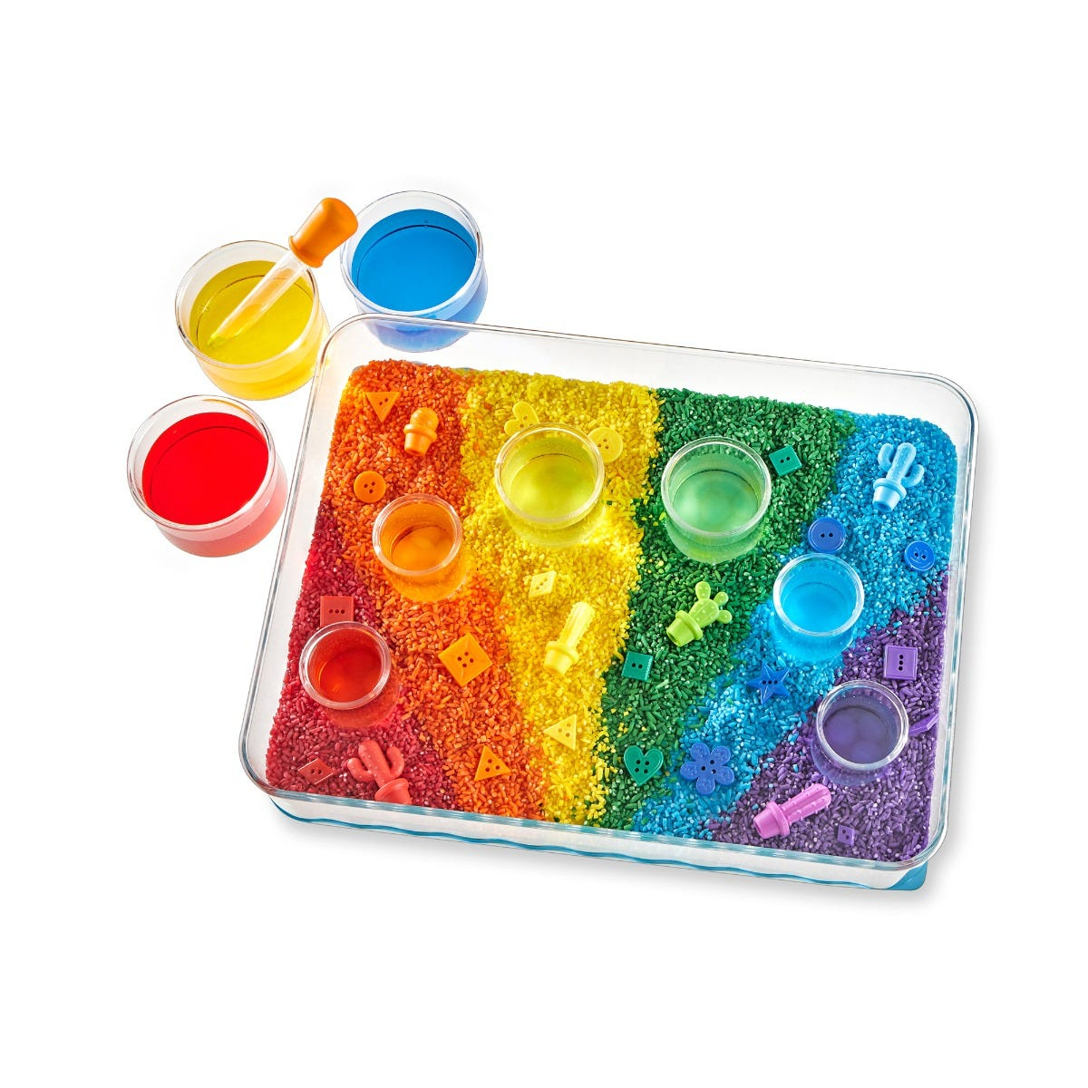 Eine Sinneskiste mit buntem Regenbogenreis, kleinen Bechern mit farbiger Flüssigkeit, einer Pipette und Formen.