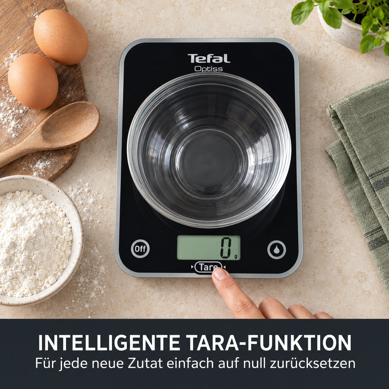 Digitale Küchenwaage von Tefal mit leerer Schüssel, Eiern, Mehl und einem Geschirrtuch.