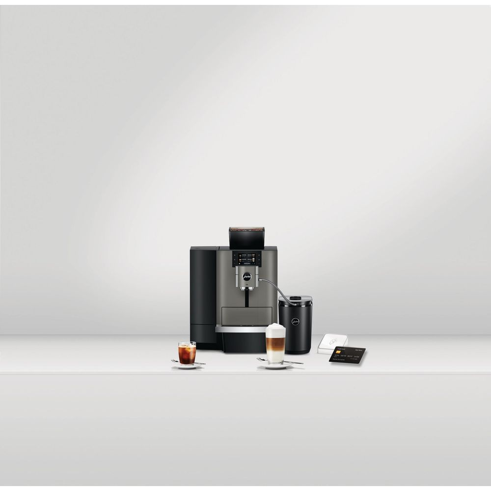 Moderne Kaffeemaschine auf weißem Tisch mit Latte Macchiato, Eiskaffee und einem Kartenlesegerät mit Kreditkarte.