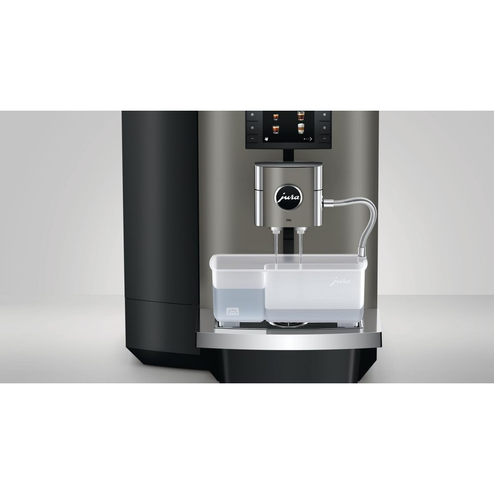 Ein Jura-Kaffeevollautomat reinigt die Ausläufe mit einem transparenten Behälter auf der Abtropfschale.
