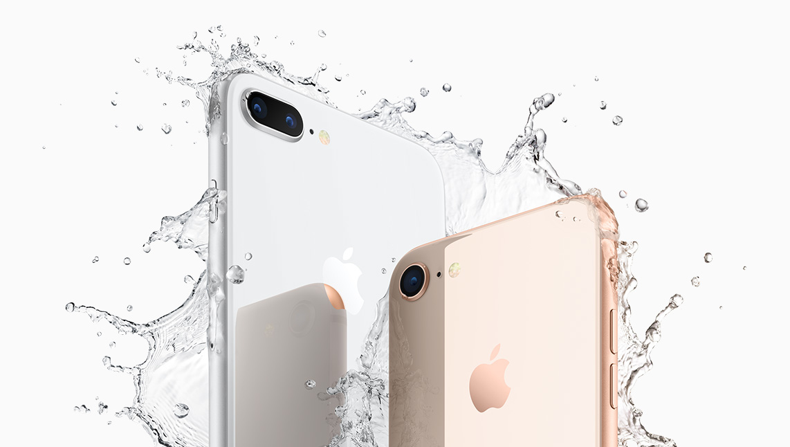Zwei iPhones in weiß und gold stehen in einem plätschernden Wasserspritzer vor weißem Hintergrund.