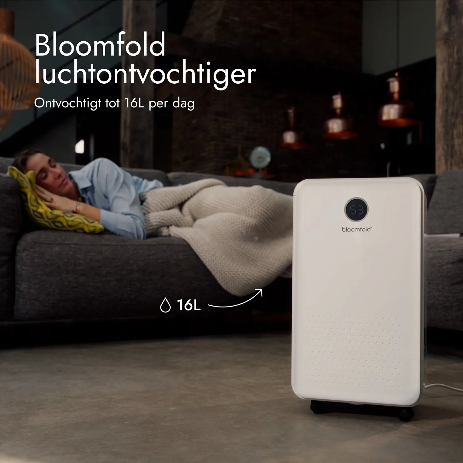 Ein weißer Bloomfold-Luftentfeuchter steht in einem Raum, während eine Frau auf einem Sofa schläft.