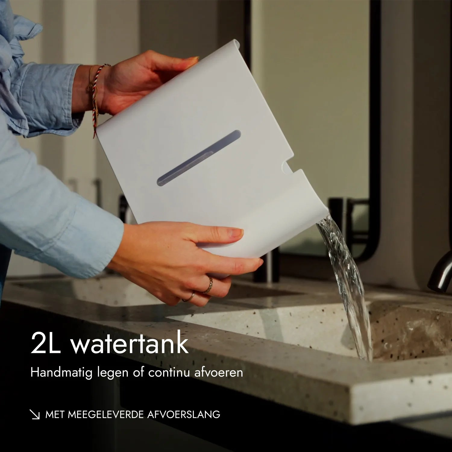 Eine Person leert einen weißen 2L-Wassertank in ein Waschbecken.