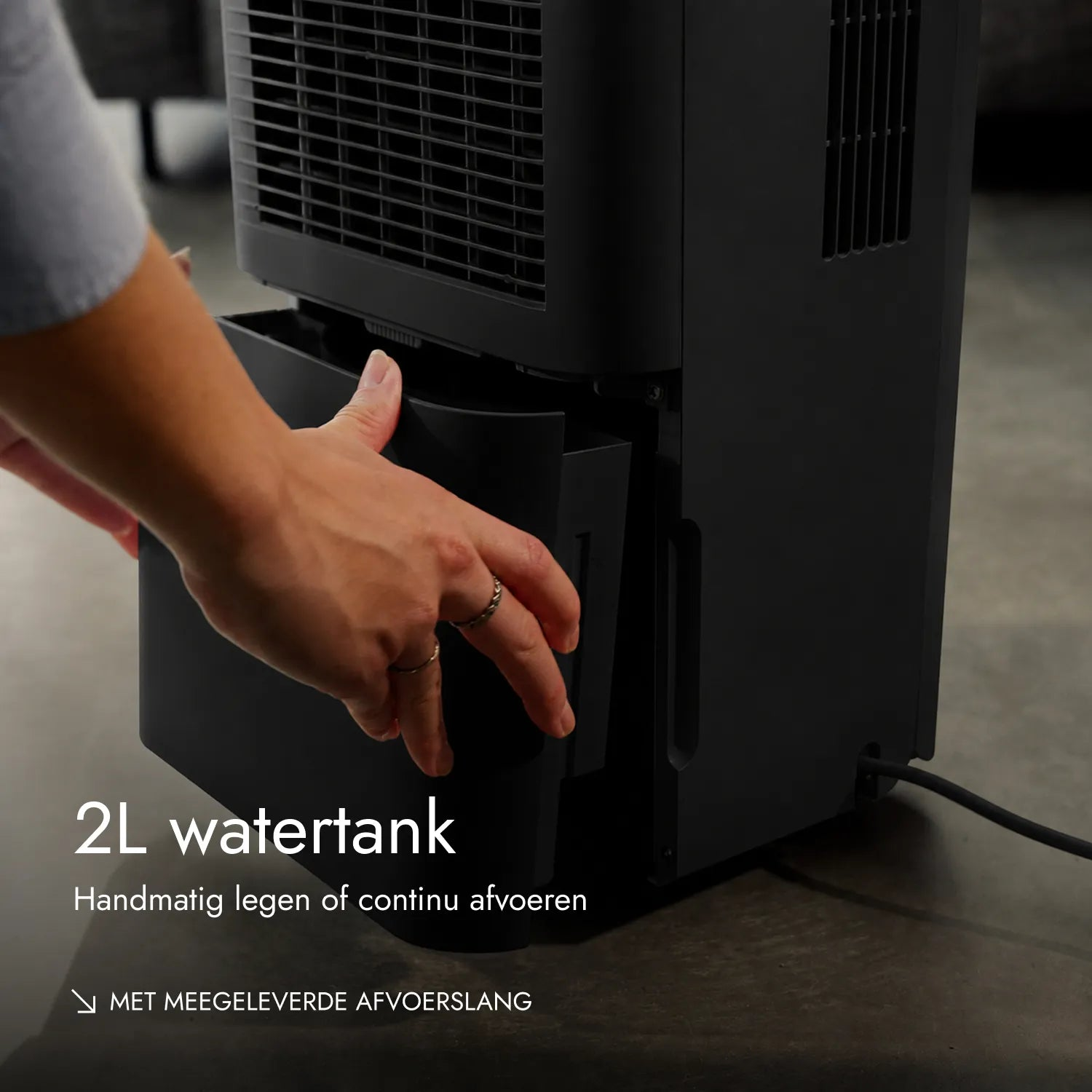 Eine Person zieht den 2L Wassertank aus einem schwarzen Luftentfeuchter.