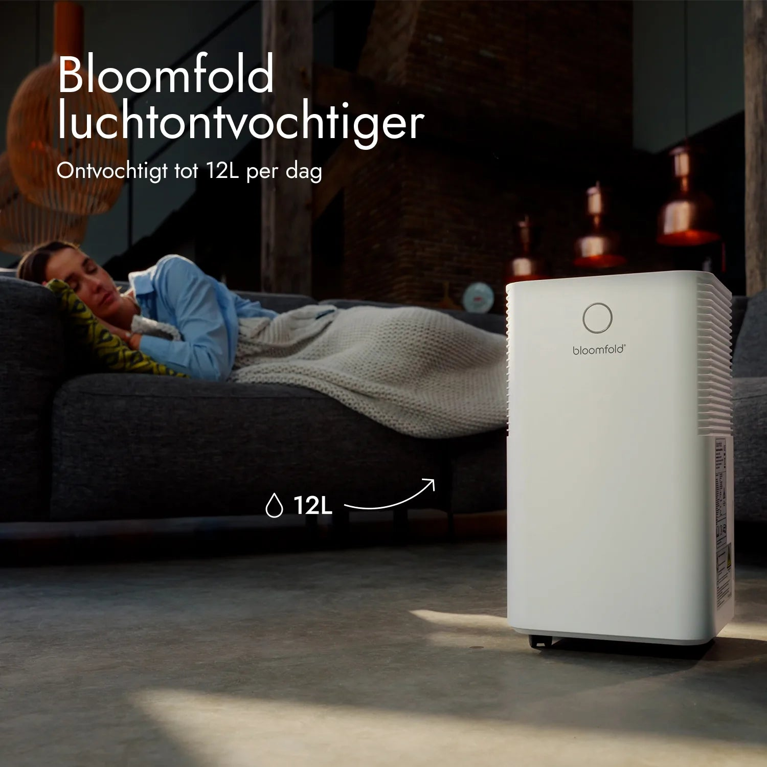 Ein weißer Bloomfold-Luftentfeuchter steht auf dem Boden, während eine Frau auf einem Sofa schläft.
