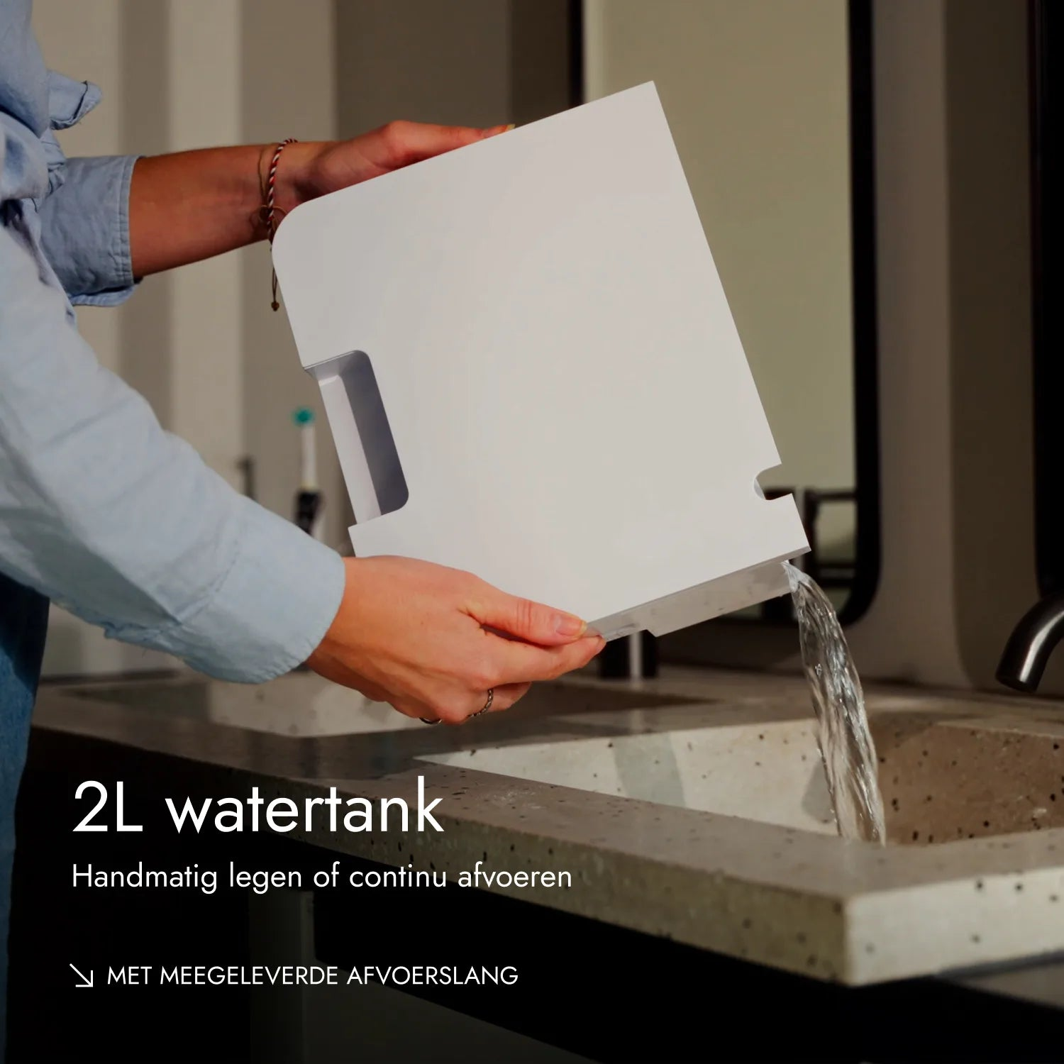 Person giesst Wasser aus einem weissen 2L-Wassertank in ein Betonwaschbecken.